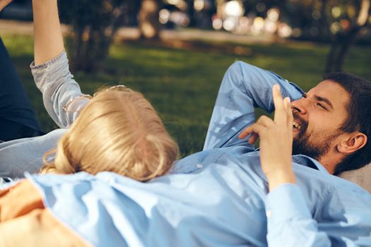A man and a woman lie in the park on the grass with a phone in their hands rest communication. High quality photo