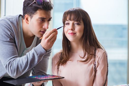 Man doing make-up for cute woman in beauty salon