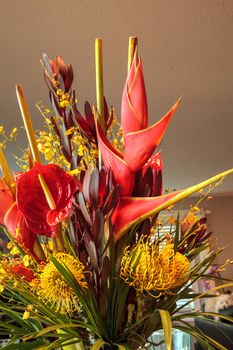 Tropical bouquet of flowers including Heliconia bihai, yellow oncidium orchids, yellow pincushion protea, and red anthuriums.