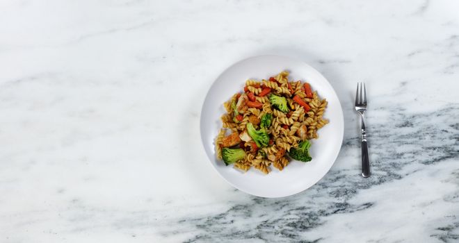 Dinner plate filled with healthy vegetables and noodles plus fork as eating utensil 