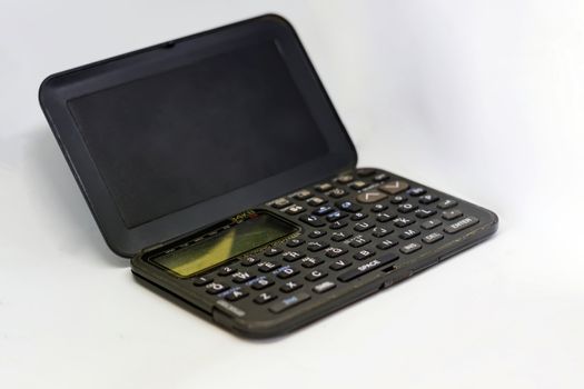 Old electronic organizer with liquid crystal display with the flap open isolated on a white background. Obsolete technology of the 90s