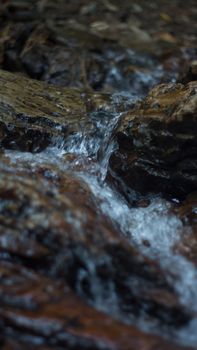 Close up of mountain river flows between picturesque summer stones. Rocks in the mountains with water flowing