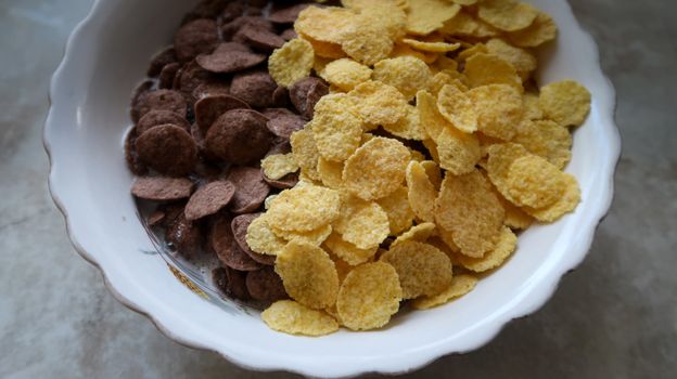 Bowl of black and yellow cereals on grey background side view