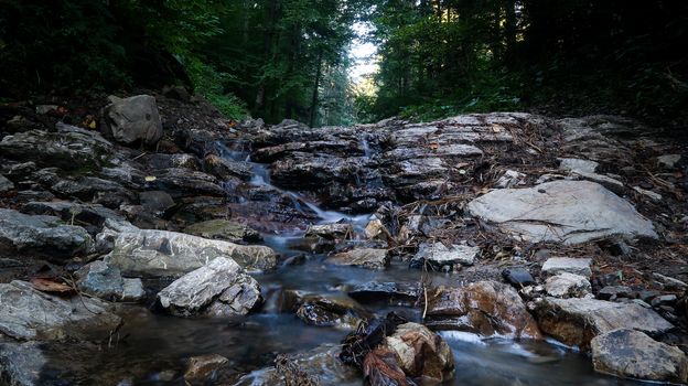 Mountain river flows between picturesque summer stones. Rocks in the mountains with water flowing