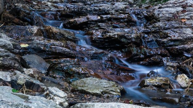 Close up mountain river flows between picturesque summer stones. Rocks in the mountains with water flowing