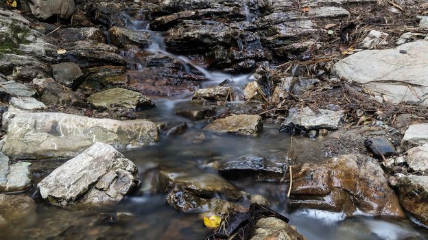 Close up mountain river flows between picturesque summer stones. Rocks in the mountains with water flowing