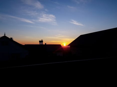 Orange sunset with clear cky and backlit shadow houses