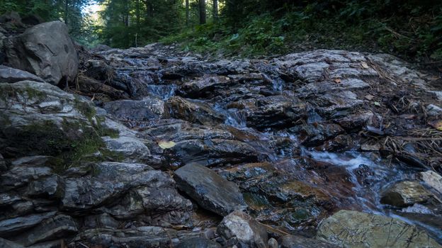 Mountain river flows between picturesque summer stones. Rocks in the mountains with water flowing