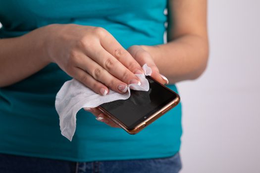 Woman holding and cleaning sanitizing phone smartphone with wet wipes