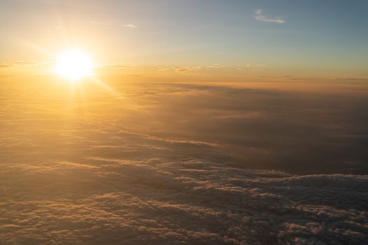 Dramatic sunset scenic. View of sunset above clouds from airplane window.