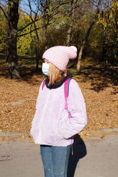 portrait of a teenage girl in a medical mask in an autumn park.