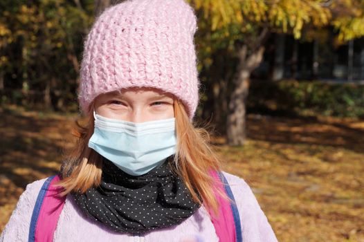 portrait of a teenage girl in a medical mask in an autumn park.