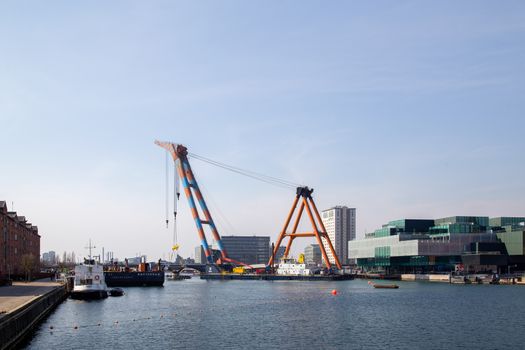 Copenhagen, Denmark - April 4, 2019: The huge Floating Crane Hebo Lift 9 installing parts for a new cycling bridge over the harbour.