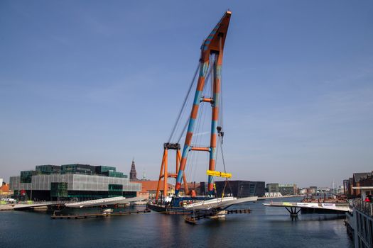 Copenhagen, Denmark - April 4, 2019: The huge Floating Crane Hebo Lift 9 installing parts for a new cycling bridge over the harbour.