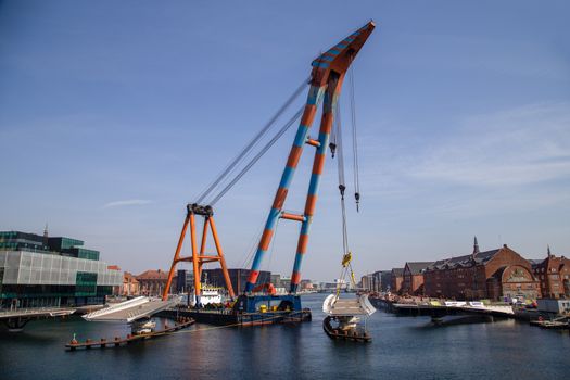 Copenhagen, Denmark - April 4, 2019: The huge Floating Crane Hebo Lift 9 installing parts for a new cycling bridge over the harbour.