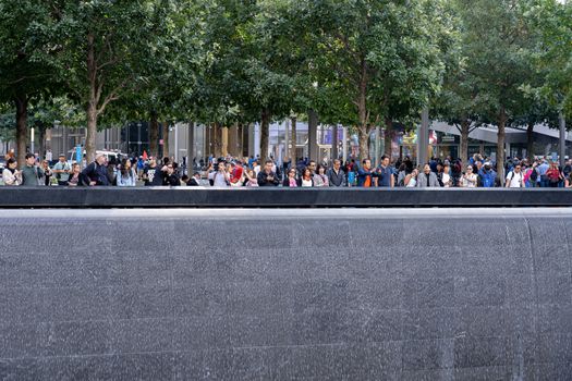 New York, United States of America - September 19, 2019: People standing at the north pool of the World Trade Center Ground Zero Memorial in Lower Manhattan.