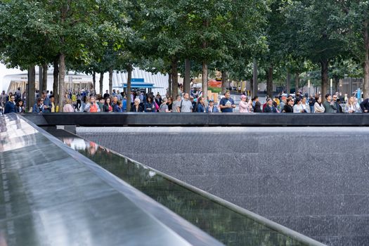 New York, United States of America - September 19, 2019: People standing at the north pool of the World Trade Center Ground Zero Memorial in Lower Manhattan.