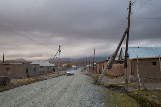 Sary-Mogul, Kyrgyzstan - October 7, 2014: Gravel road and houses in the village Sary-Mogul in South Kyrgyzstan.