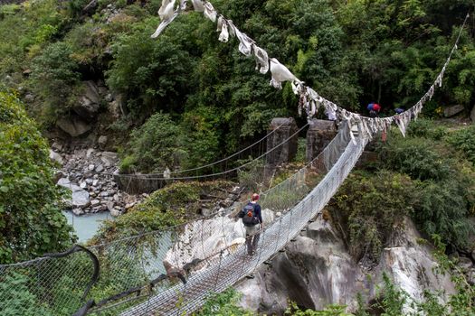 Annapurna Region - October 25, 2014: A hiker is corssing a suspension bridge in the Annapurna region