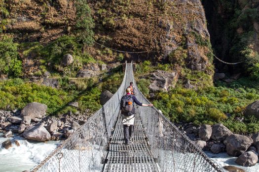 Annapurna Region - October 25, 2014: Hikers are corssing a suspension bridge in the Annapurna region