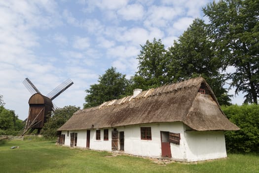 Brede, Denmark - June 23, 2016: Ancient danish farmhouse and windmill in Frilandsmuseet.