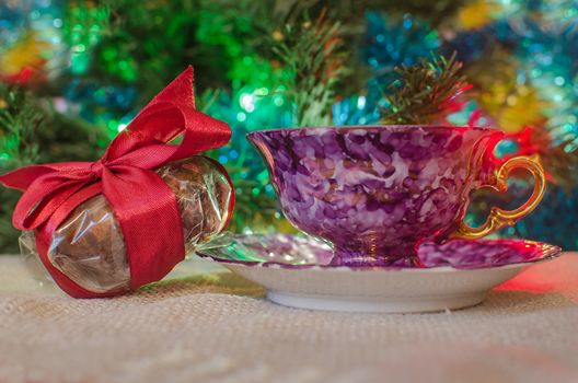 Celebration present and tea mug on blurred light backdrop. Festive decoration on lighted background