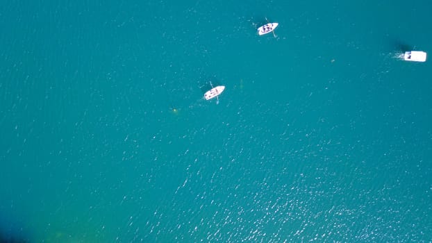 Kolsay lake among green hills and mountains. The mountain lake is surrounded by green forest, tall coniferous trees, grass and bushes. Clean water is like a mirror. Tourists swim on boats. Kazakhstan