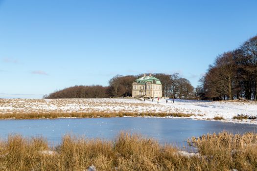 Klampenborg, Denmark - February 12, 2017: The hunting lodge and people walking in the snowy Deer Park