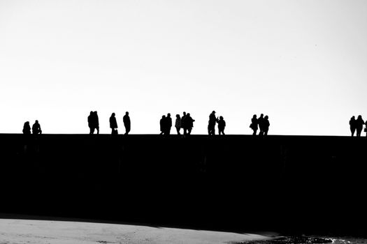 People walking and relaxing along the breakwater of a Lisbon beach