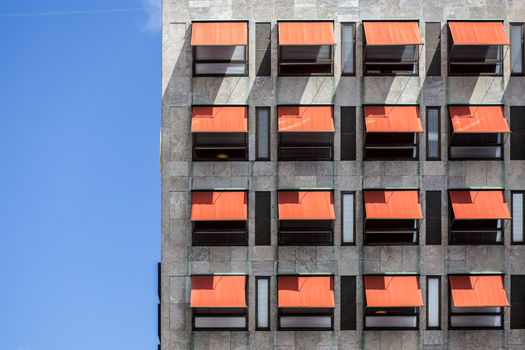 Many red awnings over windows on a office building.