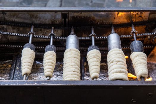 Prague, Czech Republic - March 18, 2017: Famous Czech pastry Trdelnik being baked in a street bakery. Trdelnik, also called Trdlo is a sugary sweet pastry.