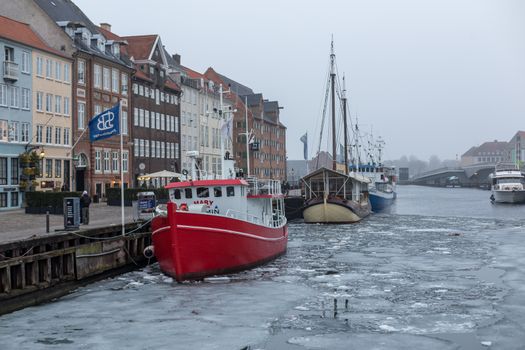 Copenhagen, Denmark - March 11, 2018: The famous Nyhavn pier with colourful buildings and boats on a frozen canal