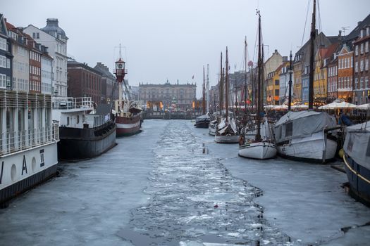 Copenhagen, Denmark - March 11, 2018: The famous Nyhavn pier with colourful buildings and boats on a frozen canal