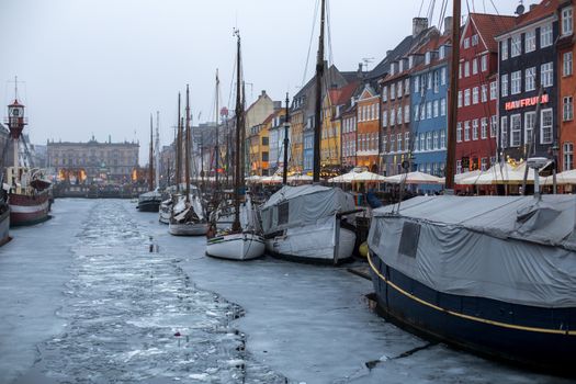Copenhagen, Denmark - March 11, 2018: The famous Nyhavn pier with colourful buildings and boats on a frozen canal