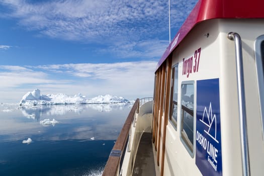 Ilulissat, Greenland - July 7, 2018: A ferry boat from the Disko Line sailing in between icebergs.