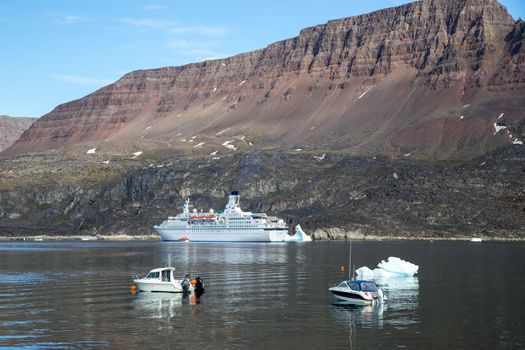 Ilulissat, Greenland - July 06, 2018: A big cruise ship and fishing boats anchored in Qeqertarsuaq harbor