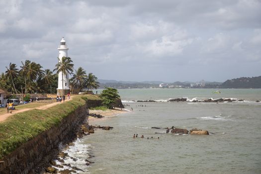 Galle Fort, Sri Lanka - July 27, 2018: The lighthouse and people walking on the fort wall