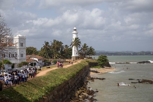 Galle Fort, Sri Lanka - July 27, 2018: The lighthouse and people walking on the fort wall