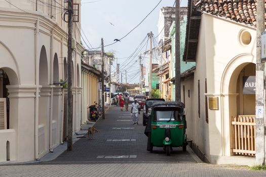 Galel, Sri Lanka - July 27, 2018: People and tuk tuks in a small cozy street in historical Galle Fort.