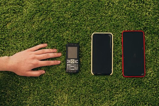 The Human Hand Picks an Old Phone That Lies Near New Smartphones.