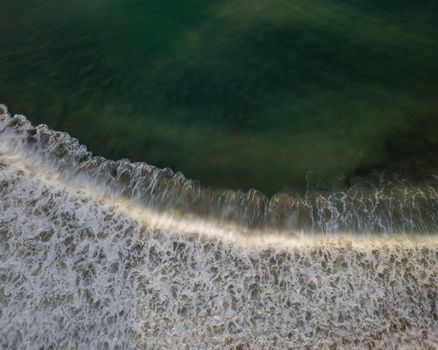 Top down aerial view of sea water and wave. Green ocean water and foam background with motion blur.