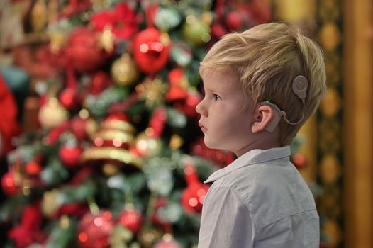 A Boy with Cochlear Implants and Christmas tree in background