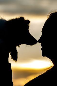 Woman and dog silhouettes on sunset clouds