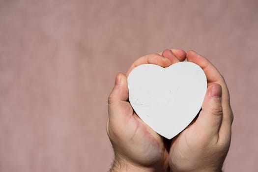 Hands holding a white wooden heart shaped object decoration isolated with copy space. Empty space template for your text.