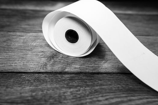 Roll of cash register tape, empty blank tax receipt on table isolated. Planning savings, spending money or business concept.