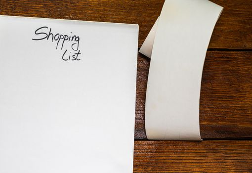 Text Shopping list on paper and empty blank tax receipt on table. Planning savings or business concept.