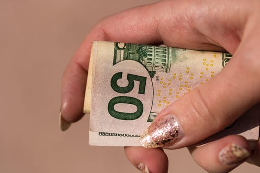 Hands giving money like a bribe or tips. Holding US dollars banknotes on a blurred background, US currency