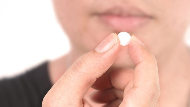 People taking or holding a white medicine pill in hand which help and protect from pandemic virus and relief them from unhealthy and sickness. studio close up shot and clear background.