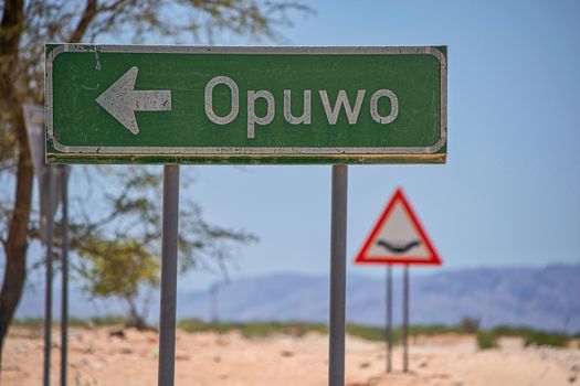 Green directional road sign to the city of Opuwo in Namibia, Africa. Travel and tourism.