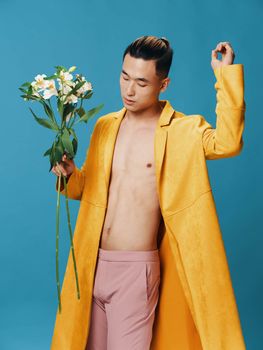 Romantic man with a bouquet of flowers on a blue background Asian model . High quality photo